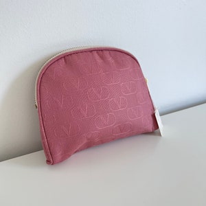 Peut inclure: Une pochette zipp&eacute;e rose avec un motif gaufr&eacute; r&eacute;p&eacute;t&eacute;. La pochette est faite d'un tissu doux et textur&eacute;.