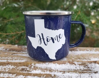 May include: Blue enamel camping mug featuring a white outline of the state of Texas with the word "Home" inside the state.