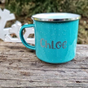 May include: A turquoise blue enamel camping mug with a silver rim and a white speckled finish. The mug has the name "Chloe" written in silver lettering.
