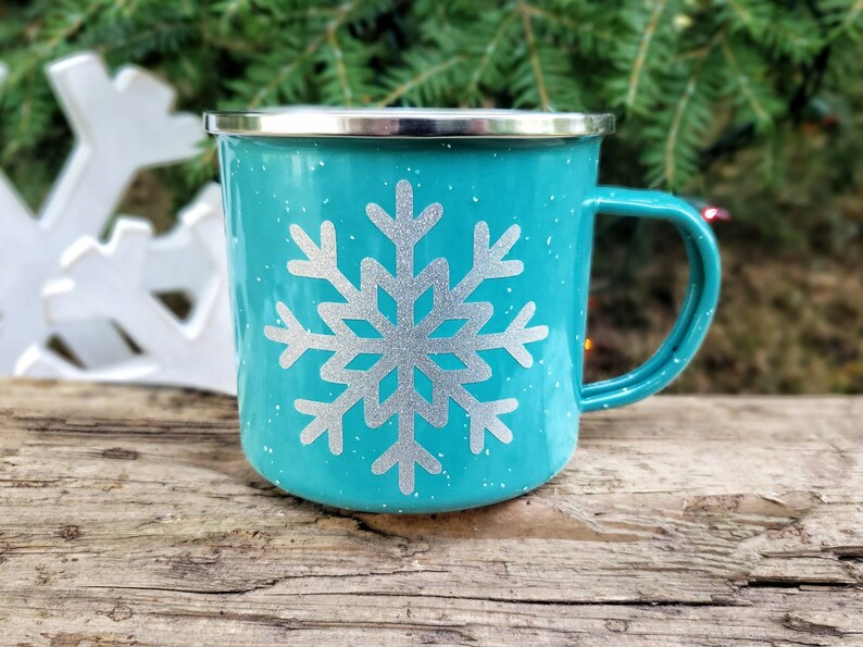 May include: A turquoise enamel mug with a silver snowflake design. The mug has a white speckled finish.