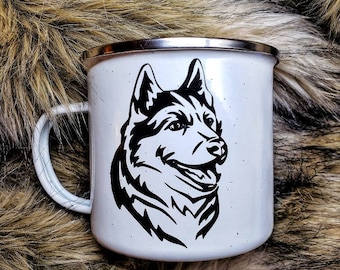 May include: White enamel mug with a black and white silhouette of a husky dog's head. The mug has a silver rim and handle.