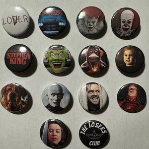May include: A selection of circular button badges with horror film imagery. The badges display images of a clown, a dog, and text including "LOVER" and "THE LOSERS CLUB".