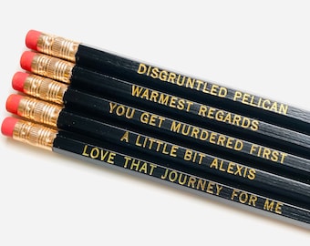May include: Set of five black pencils with gold lettering. The pencils have the following text: "Disgruntled Pelican", "Warmest Regards", "You Get Murdered First", "A Little Bit Alexis", and "Love That Journey For Me".