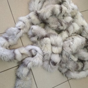 Puede incluir: Una bufanda de piel blanca y gris con un diseño largo y fluido. La piel es suave y esponjosa, y la bufanda es perfecta para añadir un toque de lujo a cualquier atuendo.