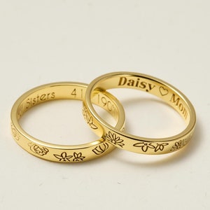 May include: Two gold rings with floral designs and engraved text. The top ring says "Daisy Mom" and the bottom ring says "4 Sisters".