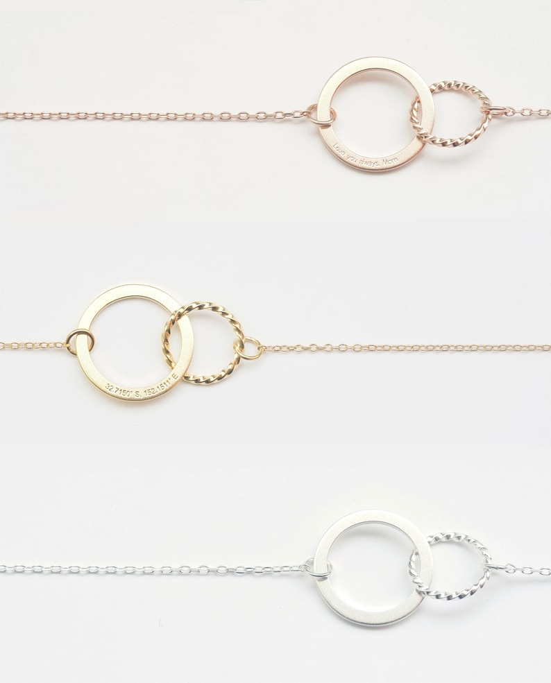 May include: Three gold necklaces with a circle pendant and a smaller circle attached to the larger circle. The larger circle on the top necklace has the inscription "Love you always, Mom". The larger circle on the middle necklace has the inscription "32.7160&deg; S, 153.1619&deg; E".