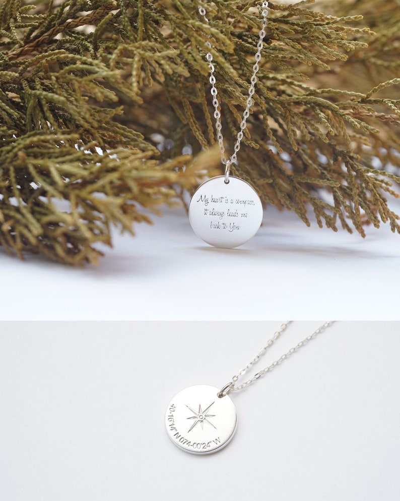 The photo has two faces of the circle necklace. The front side is engraved with a compass symbol at the center, then a coordinates underneath the compass symbol. The back side is engraved with My heart is a compass, it always leads me back to you