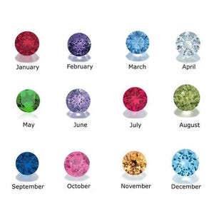 May include: A grid of twelve round, faceted birthstones arranged in three rows of four. Each stone is labeled with a month name: January (red), February (purple), March (light blue), April (clear), May (green), June (lavender), July (red), August (lime green), September (dark blue), October (pink), November (amber), and December (sky blue).