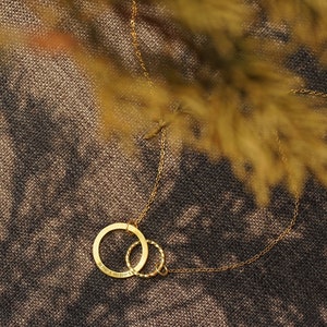 May include: A gold chain necklace with a double circle pendant. The larger circle has the inscription "21.10.15. 19.25.11."