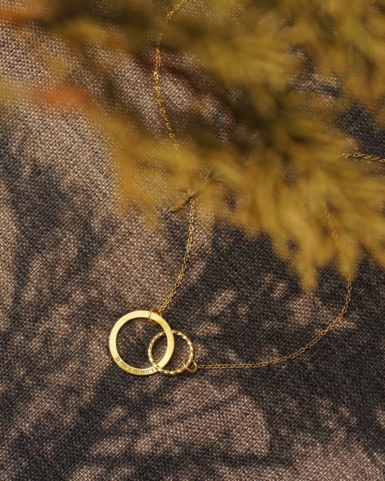 May include: A gold chain necklace with a double circle pendant. The larger circle has the inscription "21.10.15. 19.25.11."