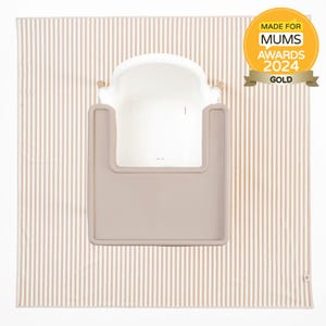 Könnte beinhalten: Ein weißer Baby-Badesitz mit einem taupefarbenen Tablett, auf einer beige-weiß gestreiften Matte. Das Bild enthält ein goldenes "Made for Mums Awards 2024 Gold" Siegel. Der Badesitz ist für die Säuglingspflege konzipiert.