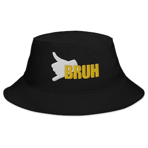 May include: Black bucket hat with a white hand pointing to the right and the word "BRUH" in yellow embroidered on the front.