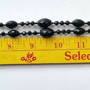 K&ouml;nnte beinhalten: Eine schwarze Perlenkette mit Quaste, gemessen auf einem Lineal mit einer L&auml;nge von 18 Zoll. Das Lineal tr&auml;gt den Text "Calico Corners" und "Selected "Seconds" of Quality Drapery".