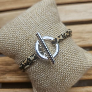 Peut inclure: Un bracelet avec un fermoir à bascule argenté et un bracelet en tissu imprimé léopard.