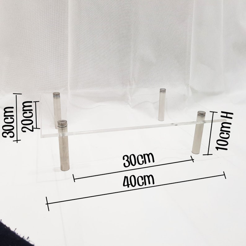 May include: Clear acrylic shelf with four silver metal legs. The shelf is 30 inches long, 40 inches wide, and 10 inches high.