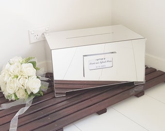 May include: A silver mirrored box with a slot on the top for cards. The box has a small white card attached to the front with the text "marriage of David and Michael Evan 11-11-2017".