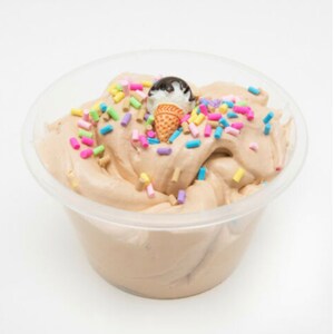 Puede incluir: Un recipiente de pl&aacute;stico transparente lleno de slime marr&oacute;n chocolate cubierto con chispas de colores y un peque&ntilde;o cono de helado de chocolate.