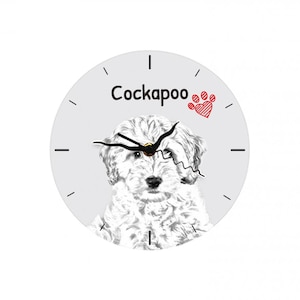 May include: A white Cockapoo dog with a black nose and eyes is featured on a round clock with black hands and a gray background. The clock has a red paw print with a heart in the center. The text "Cockapoo" is printed in black on the clock.