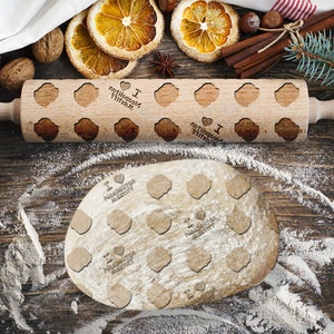 Op de afbeelding: Een houten deegroller met een patroon van harten en de tekst "I love Napoleon Bakery" erop. De deegroller ligt op een houten oppervlak met verspreid meel.