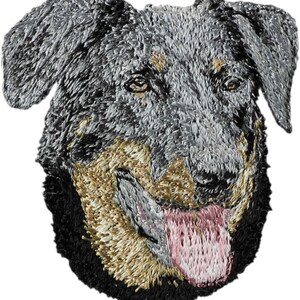 May include: Embroidered patch of a blue and tan dog with a pink tongue sticking out. The dog is looking to the right.