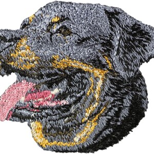 Peut inclure: Écusson brodé représentant la tête d'un chien Rottweiler. Le patch présente des coutures détaillées en nuances de gris, noir et or, avec une langue rose. La tête du chien est de profil, la langue tirée.