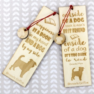 May include: Two wooden bookmarks with red string. One bookmark reads "happiness IS A BOOK in my hand AND A DOG by my side" and the other reads "outside OF A DOG A book is man's BEST FRIEND inside of a dog IT'S TOO DARK to read". Both have a Brussels Griffon dog silhouette.