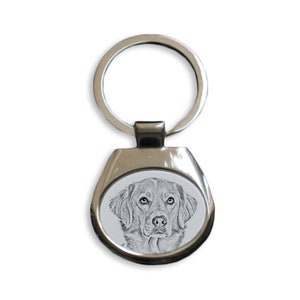 May include: A silver key chain with a black and white drawing of a dog's head on a round metal tag.