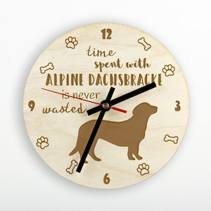 Può includere: Un orologio rotondo in legno con la scritta "time spent with ALPINE DACHSBRACKE is never wasted." L'orologio presenta una silhouette di cane marrone, impronte di zampe e grafiche di ossa. Le lancette dell'orologio sono nere e rosse.