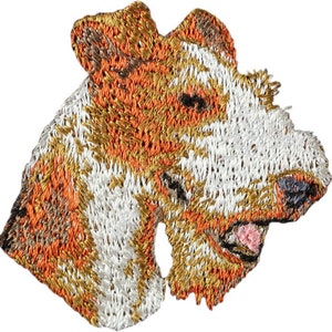 May include: Embroidered patch of a wirehaired fox terrier dog's head. The dog is white with brown and orange markings. The patch is made of felt and has a stitched border.