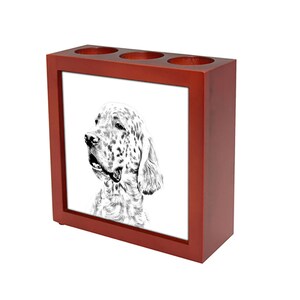 Op de afbeelding: Een rode houten potloodhouder met een witte keramische inzet met een zwart-witte illustratie van een Setter. De houder heeft drie vakken voor potloden of andere schrijfbenodigdheden.