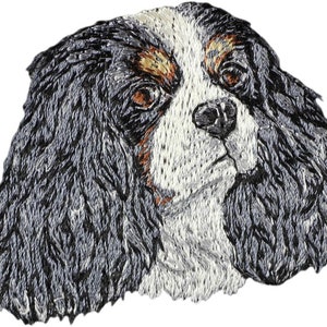 Puede incluir: Imagen bordada de un perro Cavalier King Charles Spaniel con pelaje negro, blanco y marrón. El perro mira hacia la derecha con la lengua ligeramente fuera.