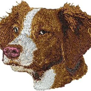 May include: Embroidered patch of a brown and white dog's head with a pink nose.