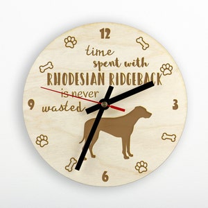 May include: A wooden clock with a brown Rhodesian Ridgeback silhouette and the text "Time spent with Rhodesian Ridgeback is never wasted". The clock face has paw prints and bone designs around the edge.