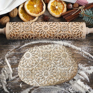 Peut inclure: Un rouleau à pâtisserie en bois avec un motif floral sculpté. Le rouleau à pâtisserie est sur une surface en bois avec de la farine éparpillée autour. Le rouleau à pâtisserie est utilisé pour créer des motifs décoratifs dans la pâte.
