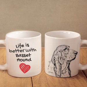 May include: Two white ceramic mugs, one with a black and white illustration of a Basset Hound and the other with the text "Life is better with Basset Hound" and a red heart.