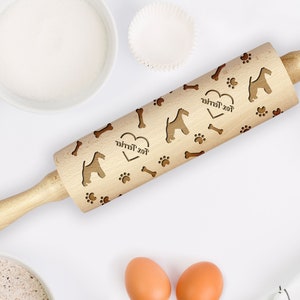 May include: A wooden rolling pin with a heart and the text "Fox Terrier" engraved on it. The rolling pin is decorated with a pattern of paw prints, bones, and fox terriers.