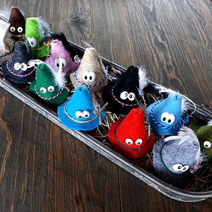 Puede incluir: Una colecci&oacute;n de sombreros de gnomo de fieltro en varios colores, incluyendo rojo, azul, verde, negro y gris. Cada sombrero tiene un pomp&oacute;n blanco y un par de ojos saltones.