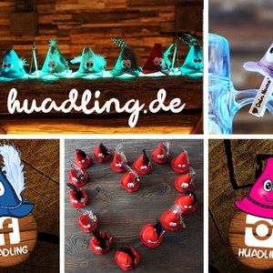 Puede incluir: Una colecci&oacute;n de sombreros de gnomo de fieltro con sombreros y caras de diferentes colores. Los sombreros est&aacute;n dispuestos en forma de coraz&oacute;n sobre una superficie de madera. Los sombreros est&aacute;n decorados con una variedad de adornos, incluyendo plumas, cuentas y botones. Los sombreros est&aacute;n disponibles para su compra en el sitio web huadling.de.