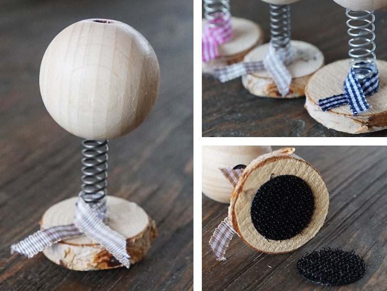 Puede incluir: Una bola de madera en un resorte con una base de madera. La base est&aacute; decorada con una cinta blanca y marr&oacute;n. La bola est&aacute; unida al resorte con un tornillo de metal.