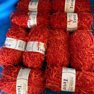 Pode incluir: Oito novelos de fio vermelho, cada um com a etiqueta "Moda Dea Tutu".