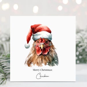 May include: A watercolor Christmas card featuring a detailed illustration of a chicken wearing a Santa hat. The card has the text "Merry Christmas Chicken" in a handwritten font, with a white background and a festive theme.