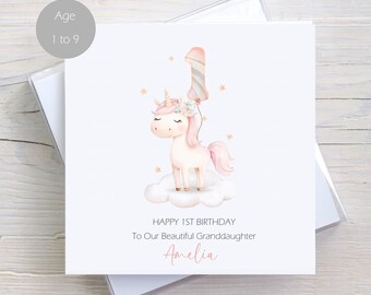 May include: A white birthday card featuring a watercolor illustration of a unicorn with a pink mane and tail, standing on a cloud. The card reads "Happy 1st Birthday To Our Beautiful Granddaughter Amelia". A gray circle indicates the card is for ages 1 to 9.