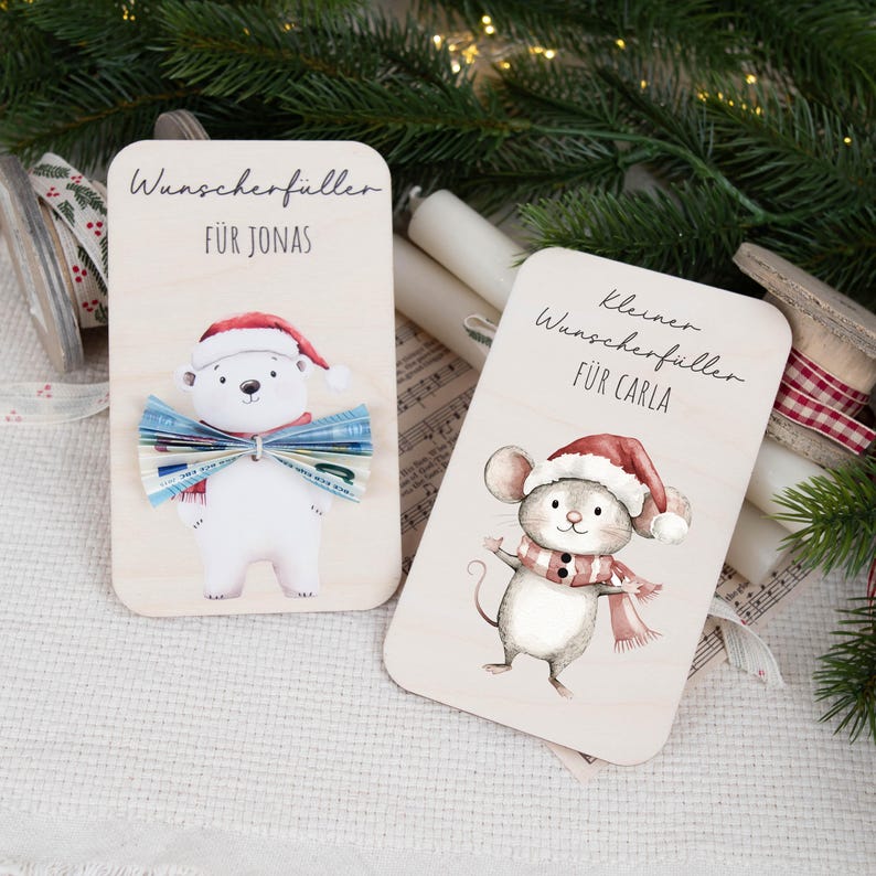 May include: Two wooden Christmas gift cards with illustrations of a polar bear and a mouse. The cards have the text "Wunschersch&uuml;ller" and "kleiner Wunschersch&uuml;ller" with names "Jonas" and "Carla" written below.