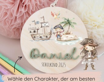Pode incluir: Decoração redonda de madeira com tema pirata com o nome "Daniel" em verde e o texto "SCHULKIND 2025". O design inclui um navio pirata, uma ilha, um papagaio e um personagem pirata. O texto na parte inferior diz "Wähle den Charakter, der am besten zu deinem Kind passt!"
