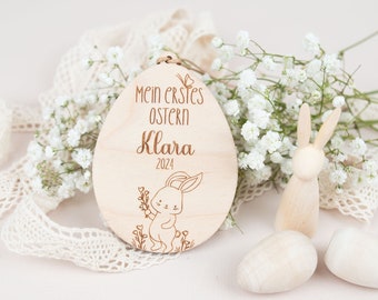 Op de afbeelding: Een houten paasei-versiering met een konijn en de tekst "Mein erstes Ostern Klara 2024".