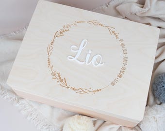 May include: A light wood keepsake box with a floral wreath design and the name "Lio" engraved on the lid. The date "05 JUL 2021 - 3:080 AM - 3.5 KG" is also engraved on the lid.