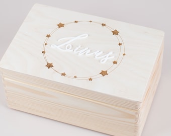 May include: A light wood keepsake box with a lid. The lid has a circle of stars engraved around the name "Linus".