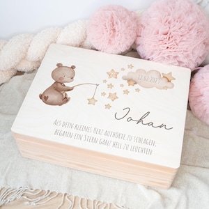 Puede incluir: Una caja de madera para recuerdos con una ilustración de un oso marrón claro sosteniendo una caña de pescar con una estrella en el extremo. La caja tiene un fondo blanco con el texto "12.02.2023", "Johan", "ALS DEIN KLEINES HERZ AUFHÖRTE ZU SCHLAGEN, BEGANN EIN STERN GANZ HELL ZU LEUCHTEN".