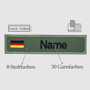 Könnte beinhalten: Ein grünes Stoff-Namensschild mit einem schwarzen gestickten Namen "Name" und der deutschen Flagge. Das Schild ist 20 cm lang und hat 30 Garnfarben.