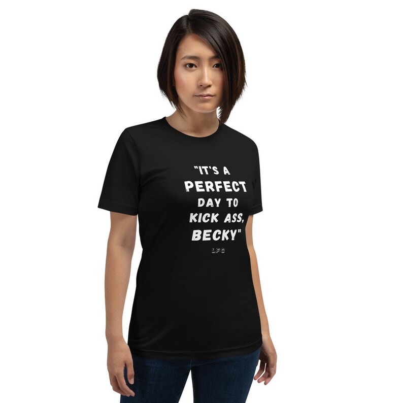 May include: Black t-shirt with the text "IT'S A PERFECT DAY TO KICK ASS, BECKY" in white. The shirt is a crew neck style and is being worn.